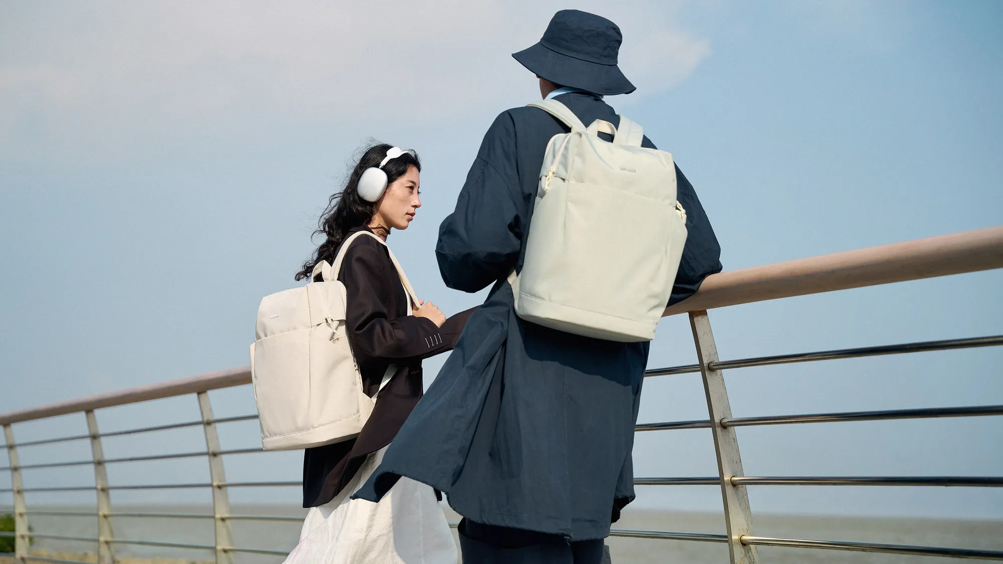 Two young travellers with MRACE backpacks by the water
