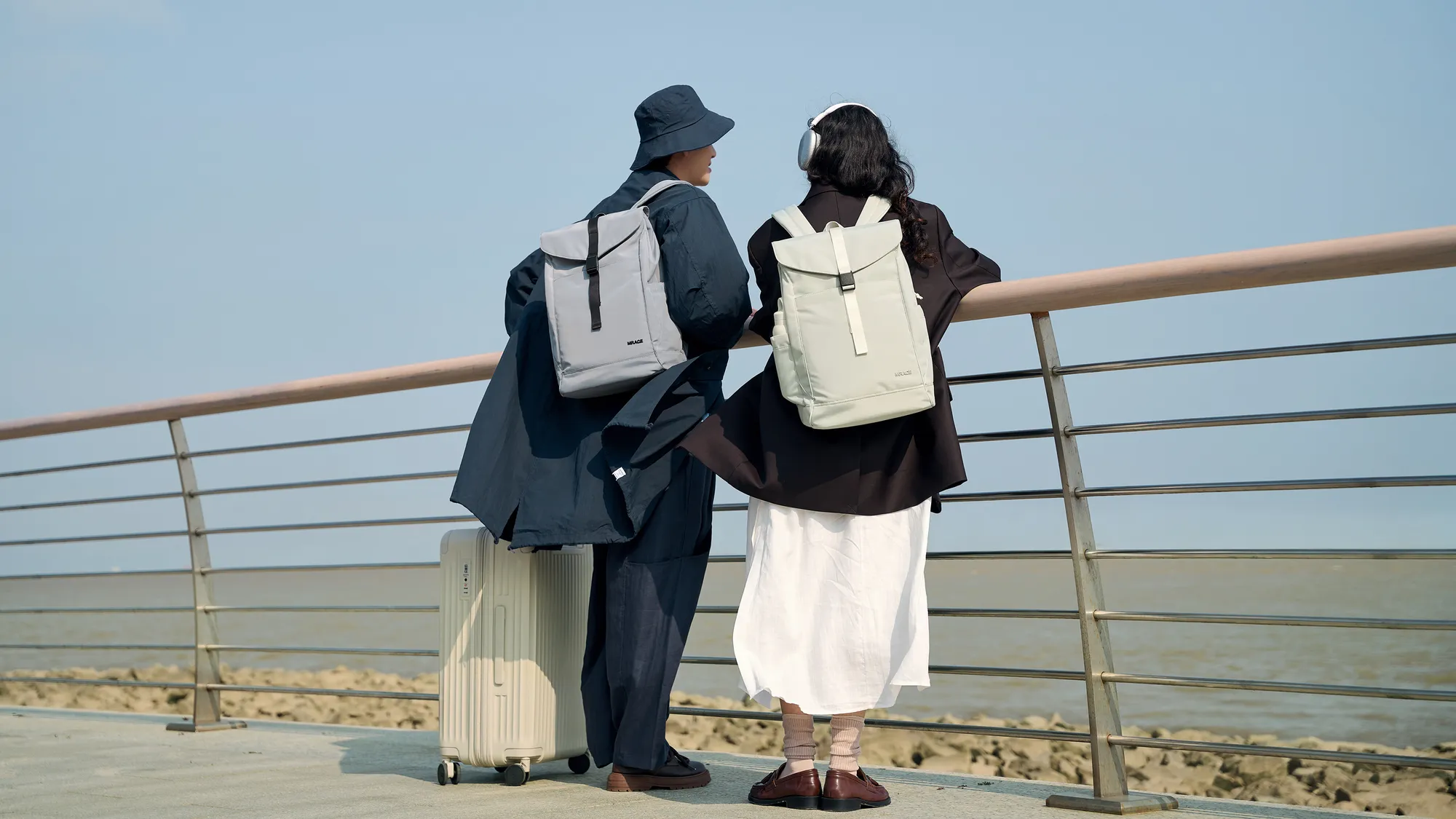Friends with MRACE bags and a suitcase on a seaside walk
